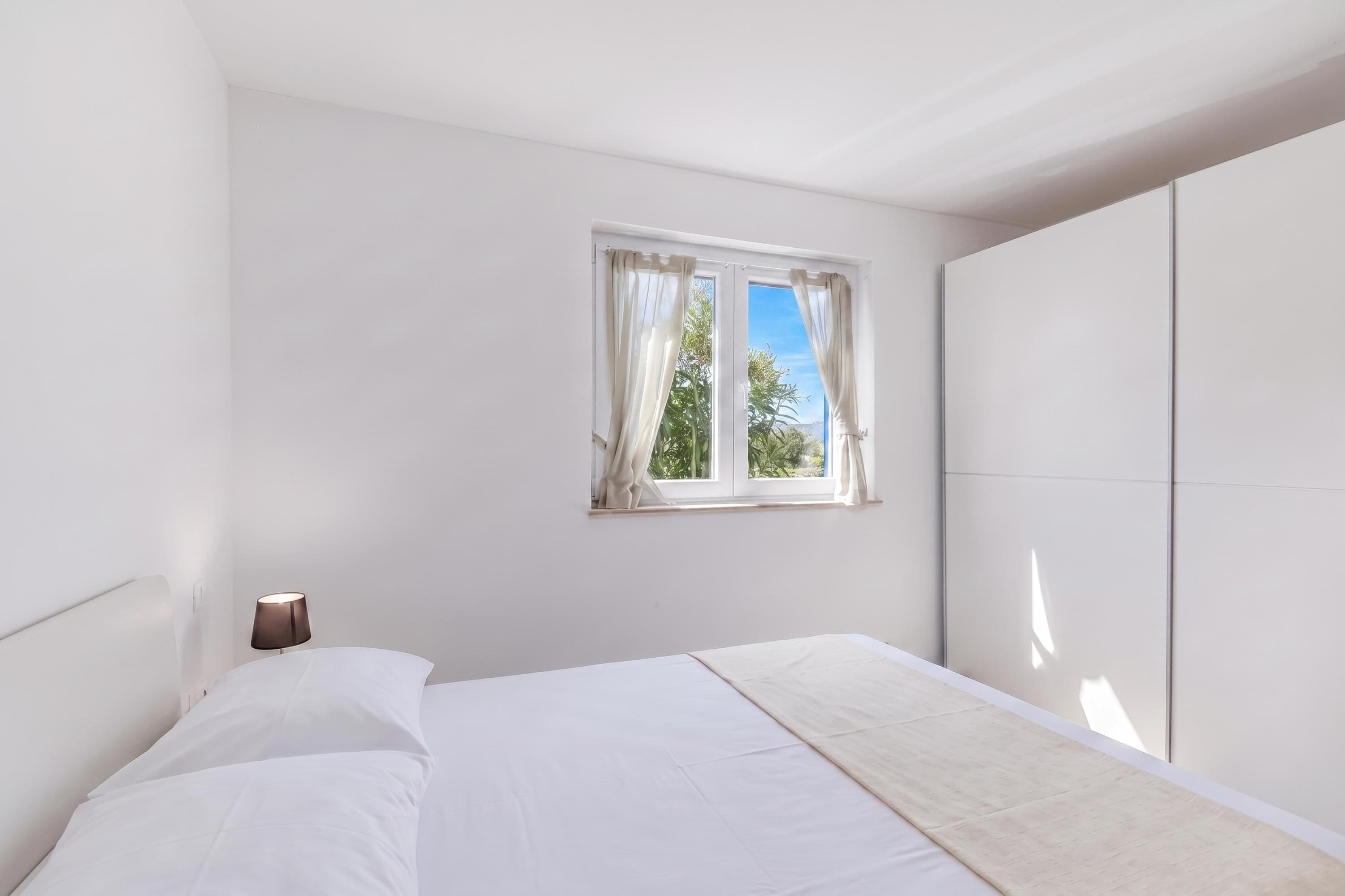 Ein Schlafzimmer mit einem Bett, einem Fenster mit Vorhängen und einem Kleiderschrank.