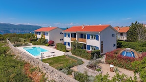 Una villa moderna con piscina, varios balcones y vistas a las montañas.