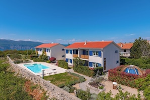 Une villa moderne dotée d’une piscine, de plusieurs balcons et offrant une vue sur les montagnes.