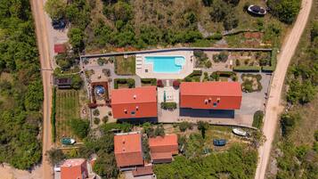 An aerial view of a residential area with multiple buildings, a swimming pool, and surrounding greenery.
