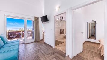 Una habitación moderna con piso de espiga, televisor de pantalla plana montado en la pared y puerta corrediza de vidrio que da a un espacio exterior con mesa y sillas.
