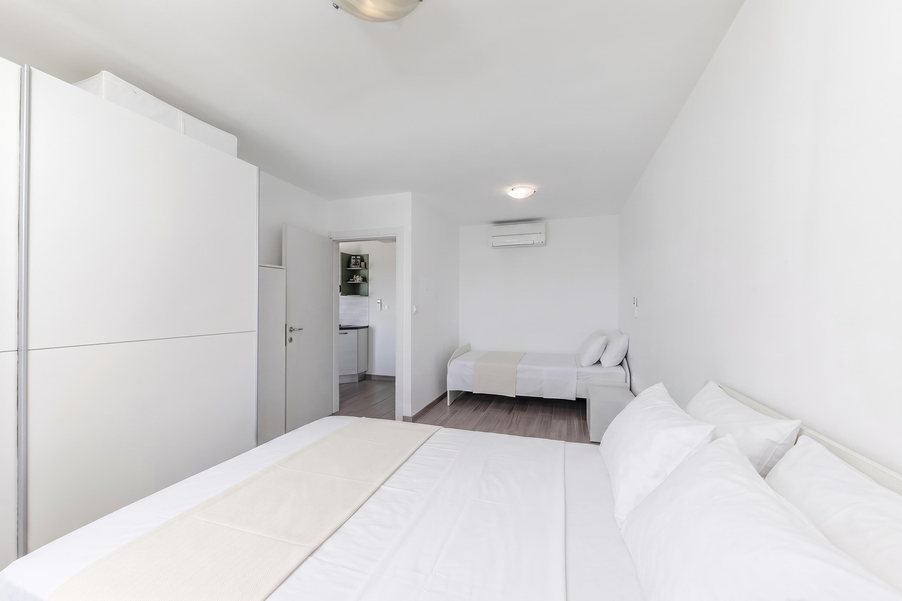 Un dormitorio con cama, armario, kitchenette pequeño y luz en el techo.