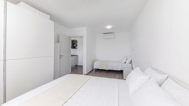 Un dormitorio con cama, armario, kitchenette pequeño y luz en el techo.