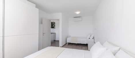 Un dormitorio con cama, armario, kitchenette pequeño y luz en el techo.