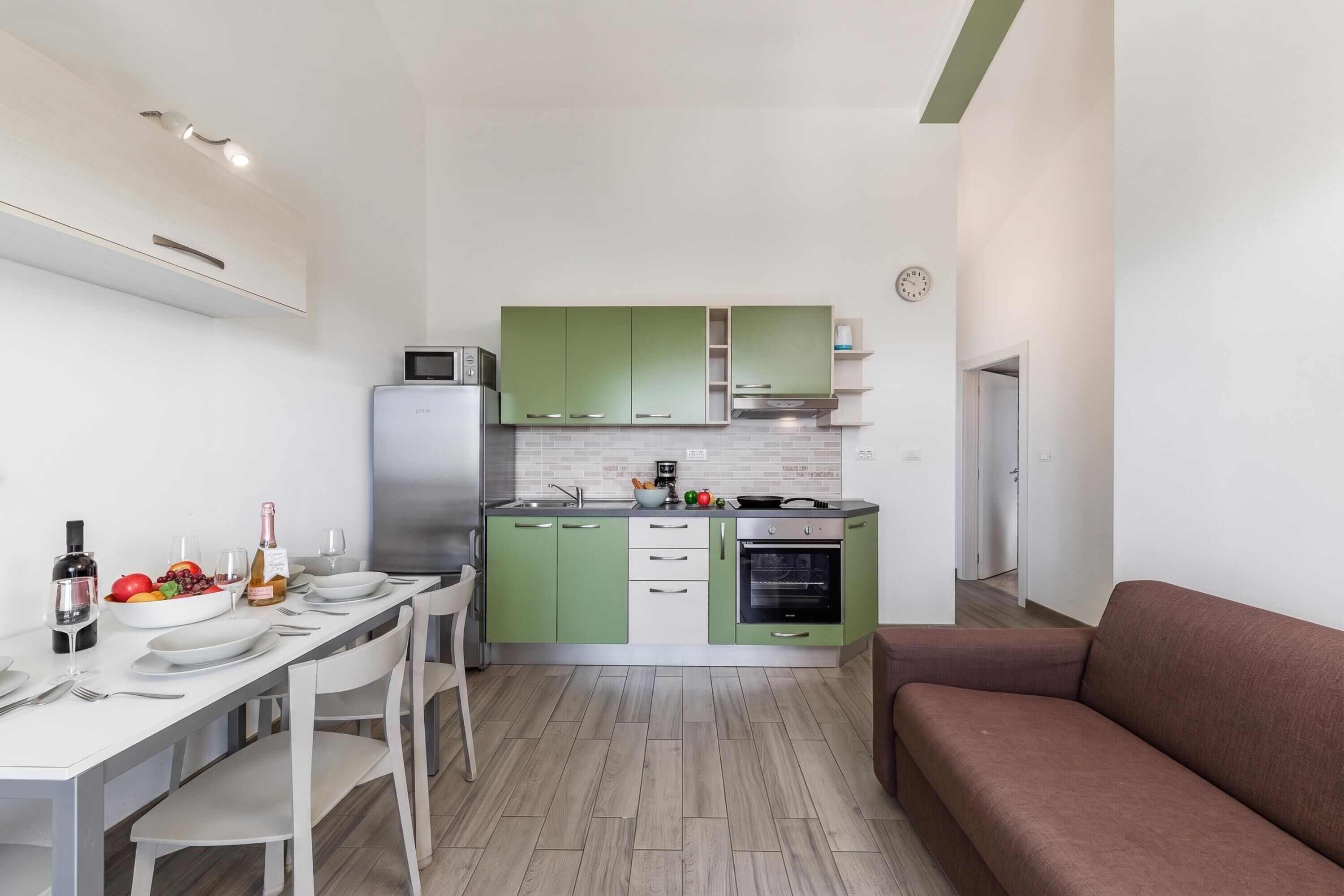 A compact kitchen with a dining area, a microwave, a refrigerator, and a built-in oven.