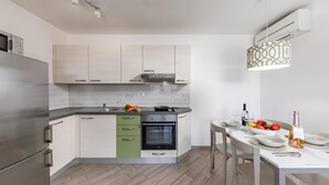 Una cocina moderna con horno empotrado, refrigerador de acero inoxidable y comedor con mesa dispuesta para dos.