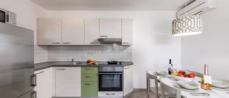 Una cocina moderna con horno empotrado, refrigerador de acero inoxidable y comedor con mesa dispuesta para dos.