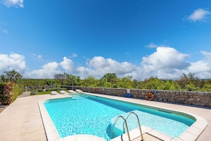 A rectangular swimming pool with a stone wall and a clear blue sky. - Wabi Sabi Apartments With Pool (Krk)
