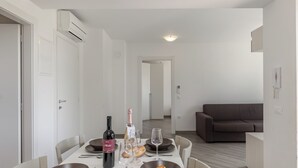 Un comedor con una mesa preparada para dos personas, una botella de vino y un croissant.