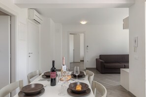 Un coin repas avec une table dressée pour deux personnes, une bouteille de vin et un croissant.