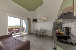 A modern kitchen with a dining area, a sofa, and a view of the outdoors. - Wabi Sabi Apartments With Pool (Krk)