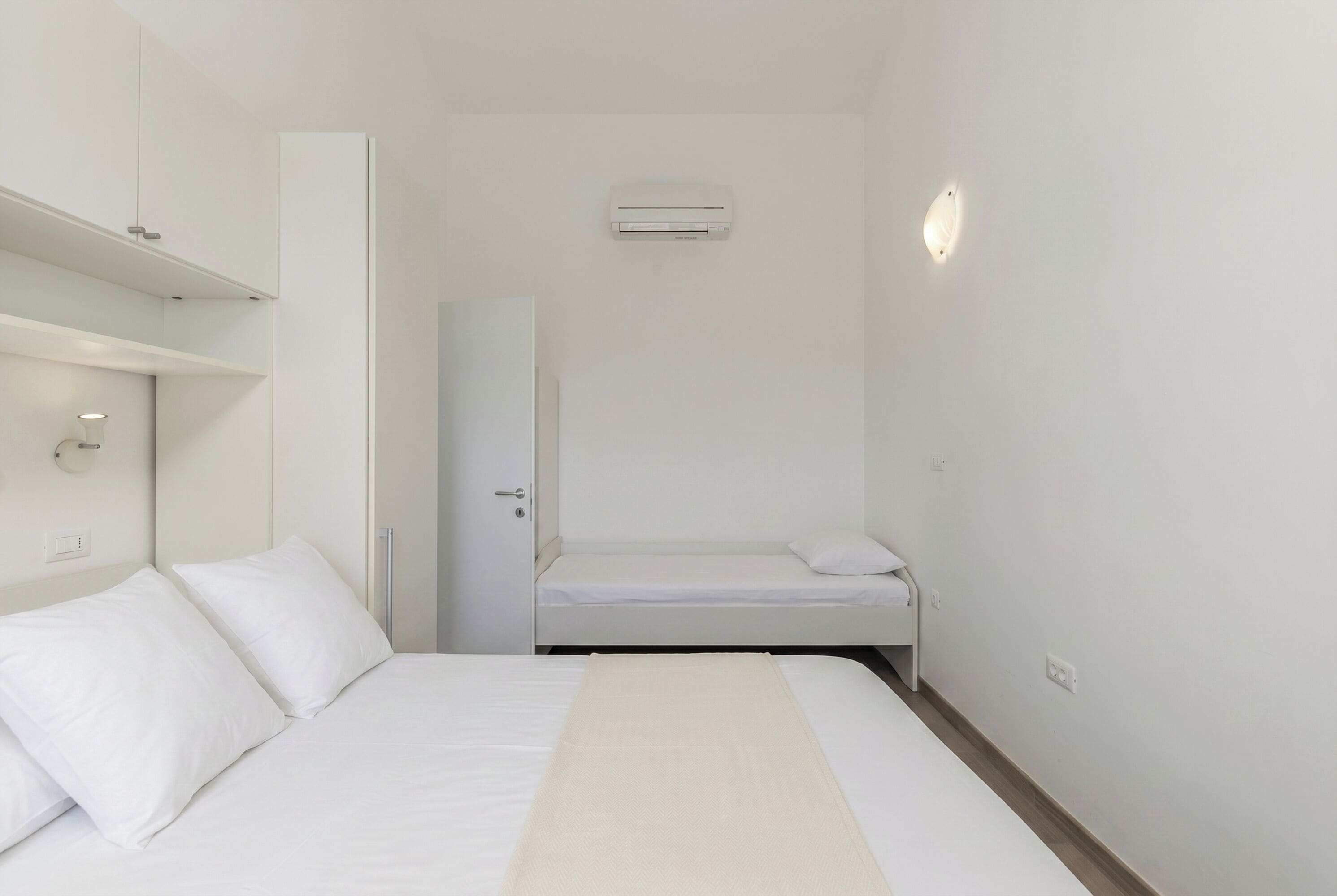 Une chambre comprenant un lit, une armoire, un miroir et un appareil de climatisation.