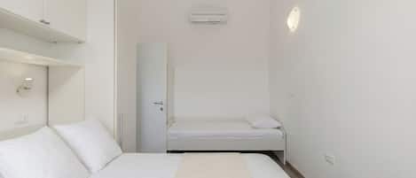 Une chambre comprenant un lit, une armoire, un miroir et un appareil de climatisation.