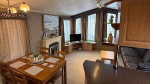 A compact living space with a dining area, a fireplace, a television, and a sofa. - Cabin Caravan Sleeps 6 With Parking (Abergele)