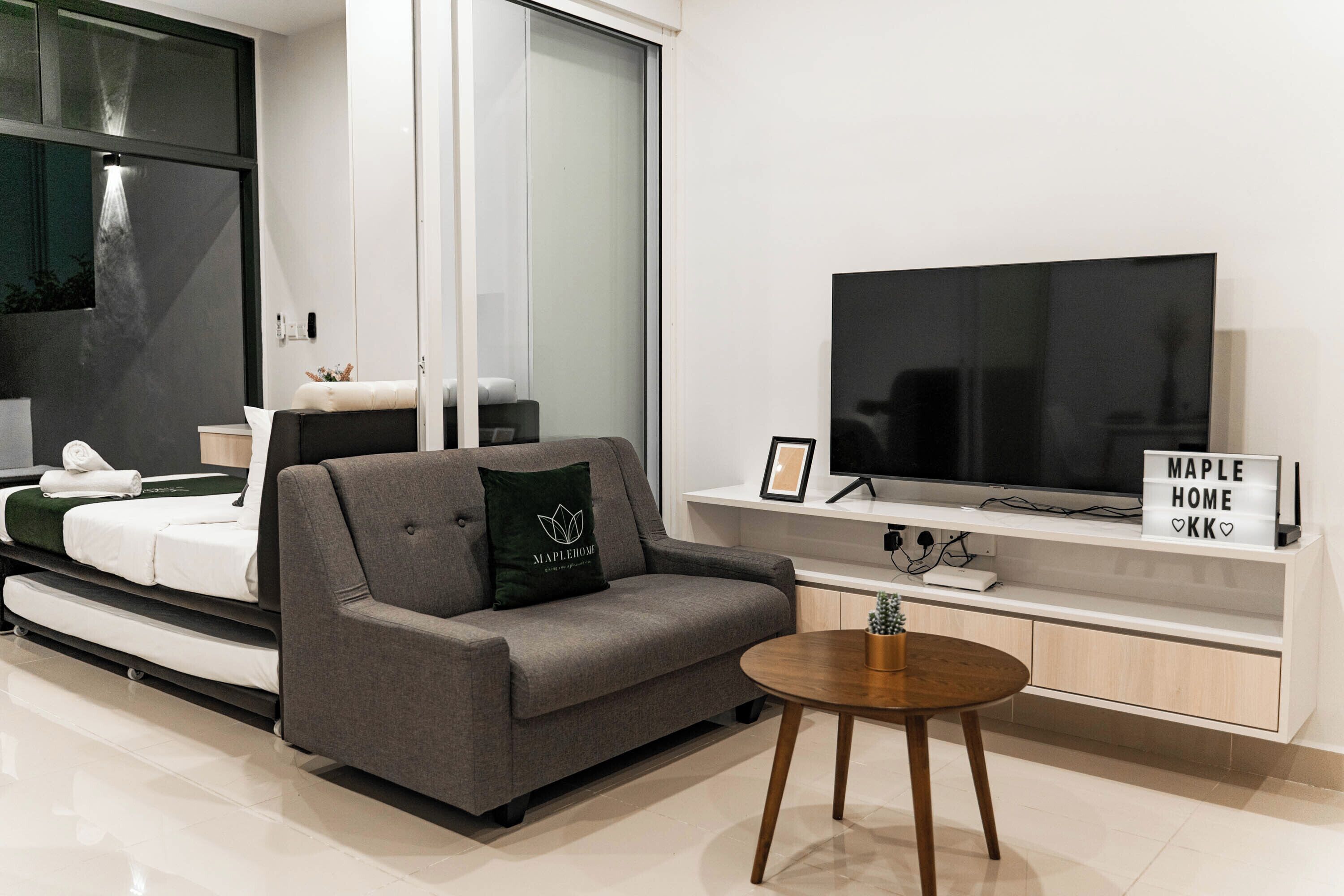 A modern living room with a sofa, a coffee table, a TV, and a sign that reads 'Maple Home.'