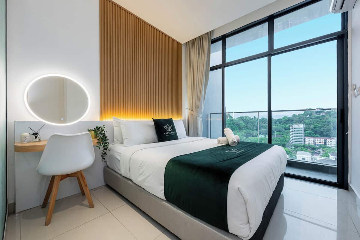 Un hotel moderno con una cama grande, un escritorio con una silla, un espejo redondo y vistas a la ciudad a través de amplias ventanas.