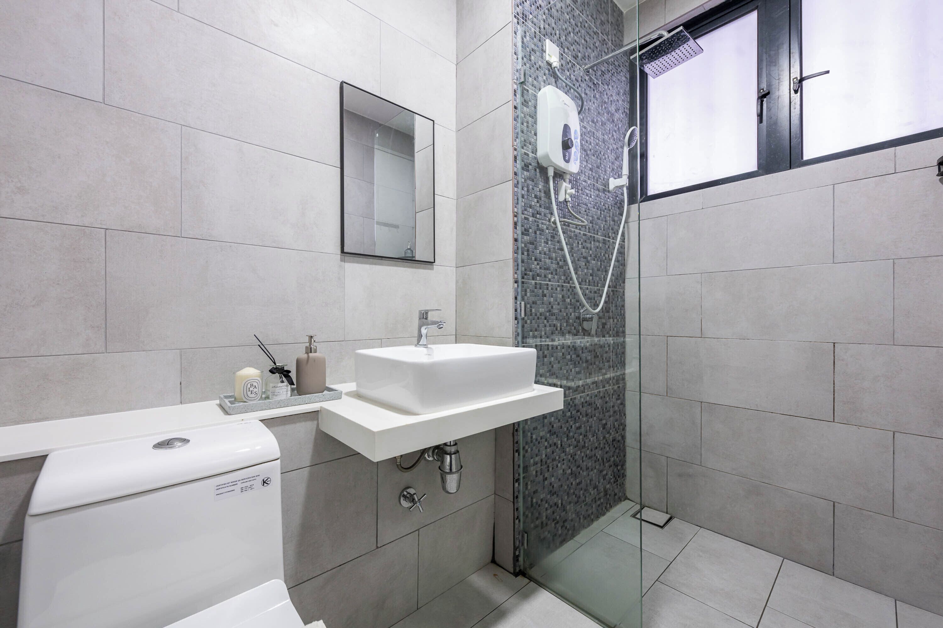 A modern bathroom with a toilet, sink, mirror, and shower area.