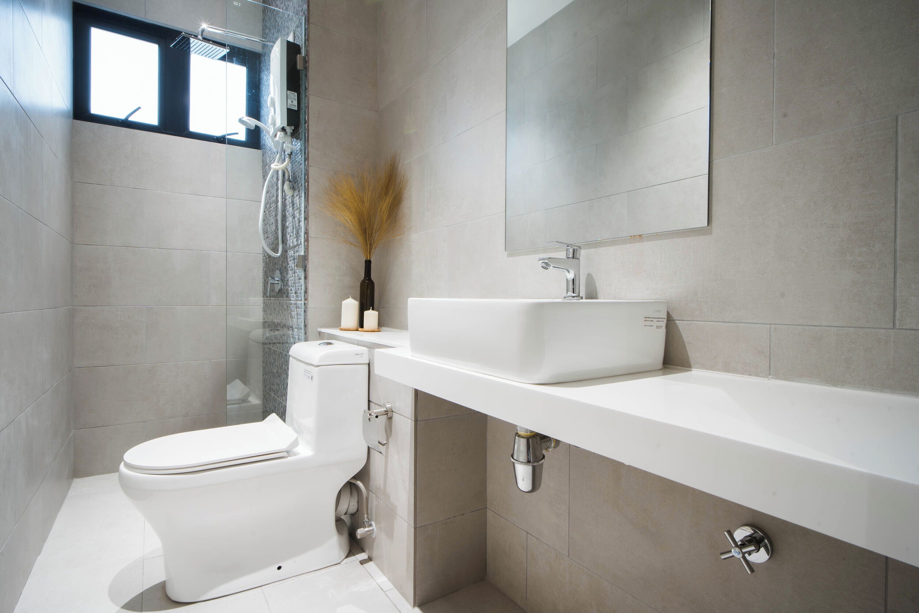 Un baño moderno con inodoro, ducha, lavamanos y espejo.