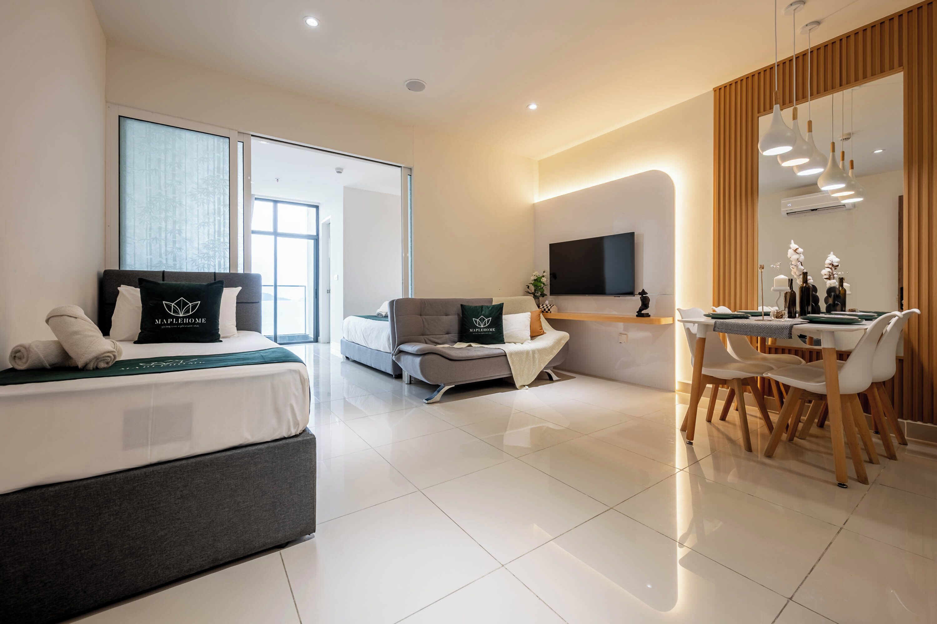 Ein modernes Hotelzimmer mit Bett, Sofa, Essbereich und Fernseher.