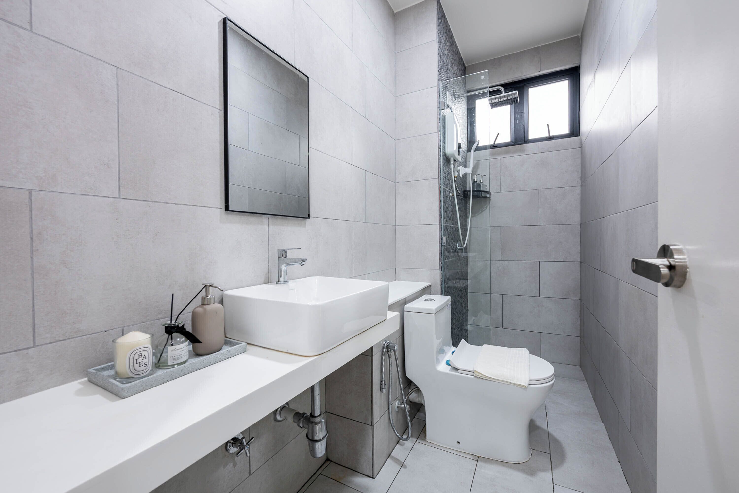 A modern bathroom with a large mirror, a sink, a toilet, and a shower.