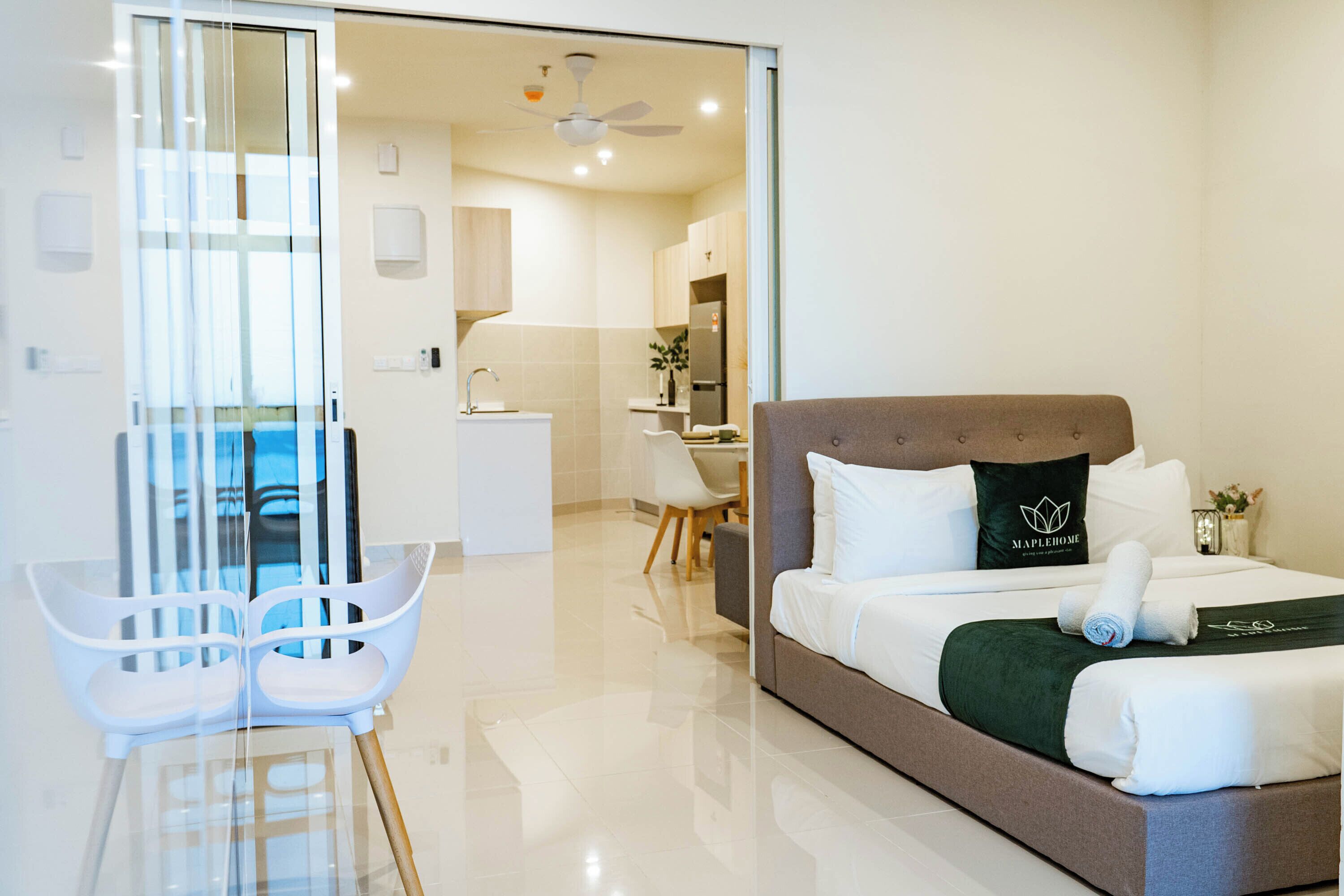 A modern hotel room with a bed, a desk, a chair, and a view of the outside.
