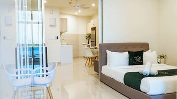 A modern hotel room with a bed, a desk, a chair, and a view of the outside.