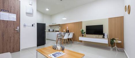 Uma sala de estar moderna com uma mesa de centro de madeira, uma televisão e um espaço de refeições com cadeiras e uma mesa.