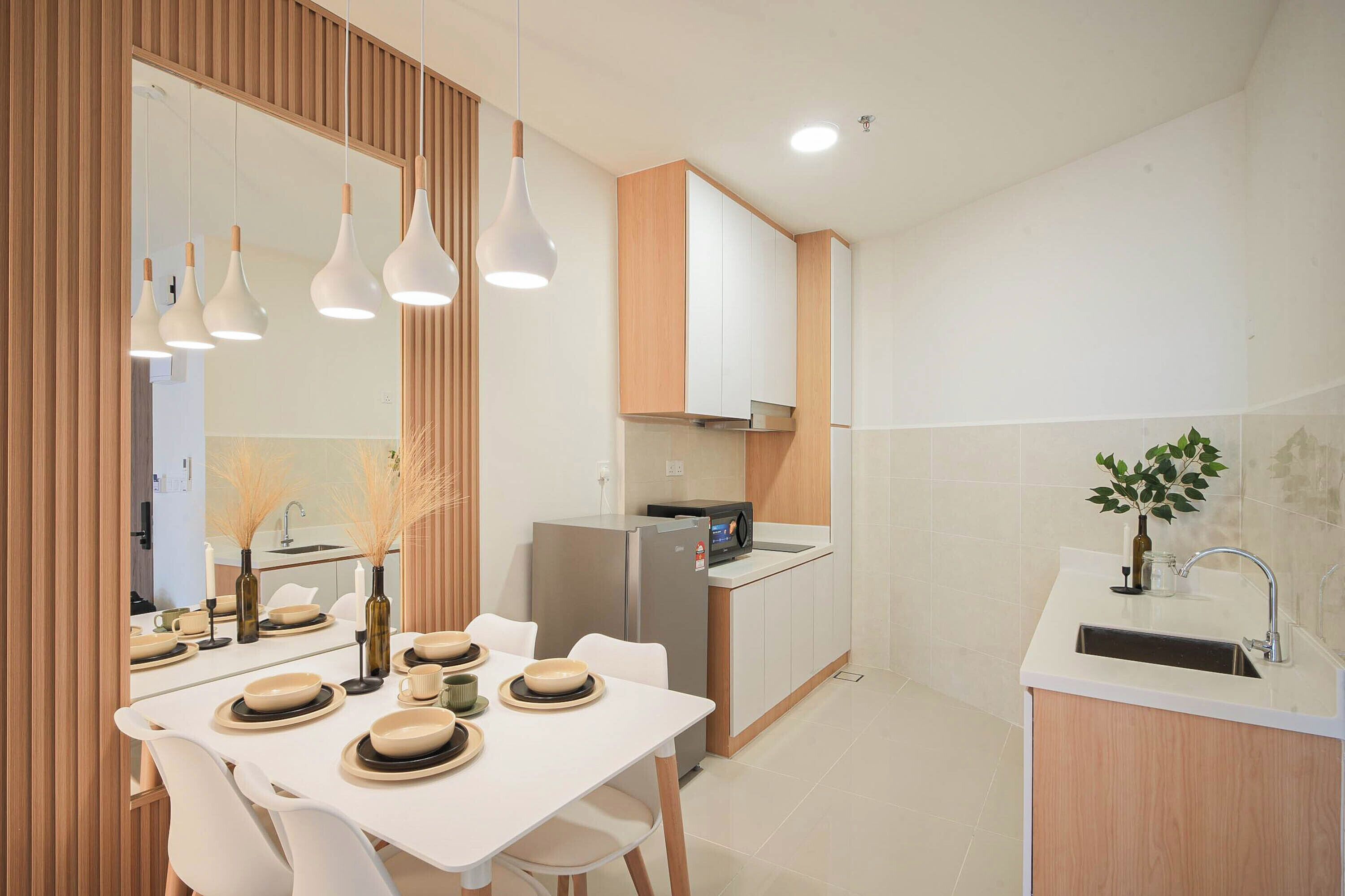 A modern kitchen with white cabinets, a stainless steel refrigerator, and a dining area with a white table set for four.