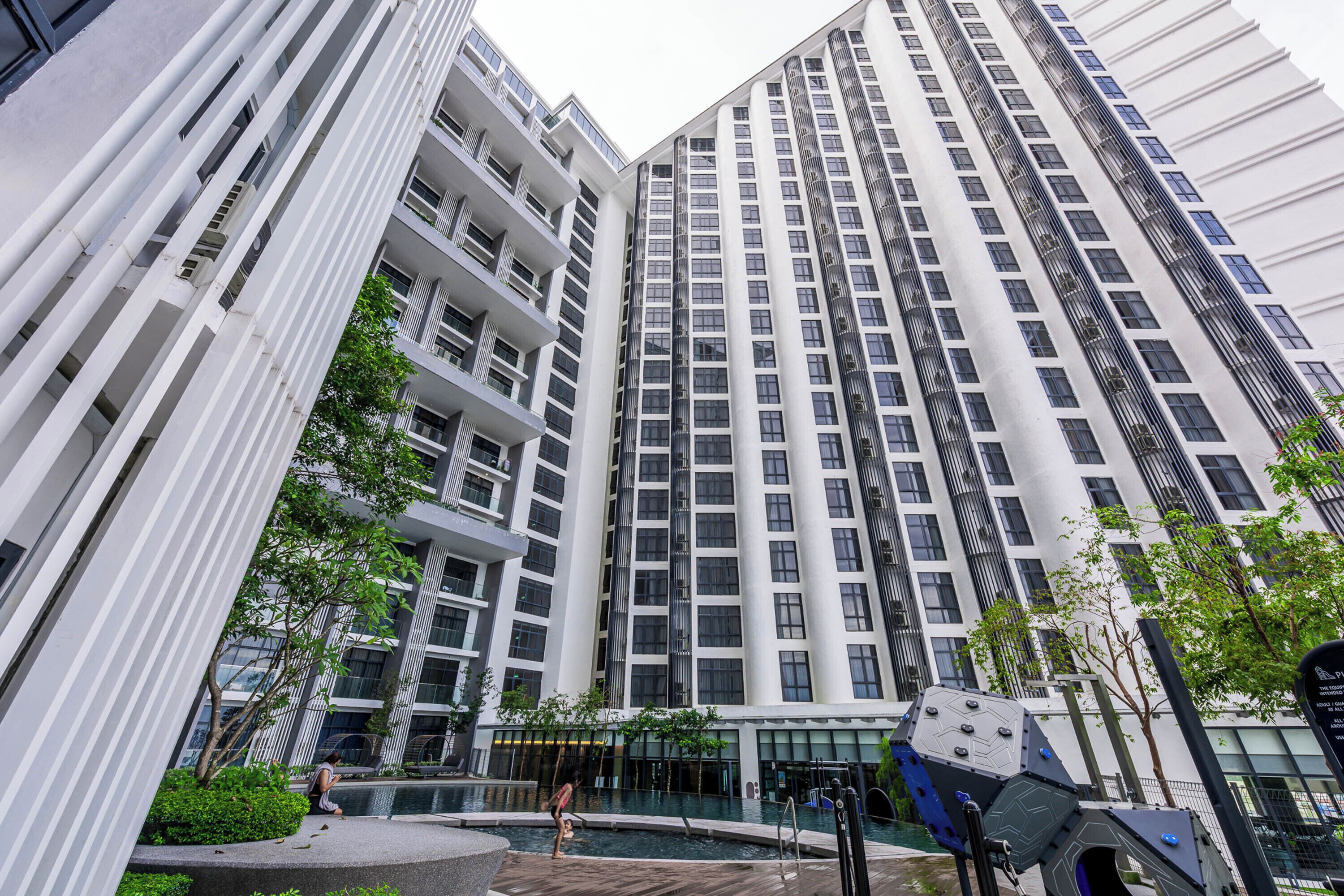 A high-rise building with multiple floors, balconies, and a swimming pool area.