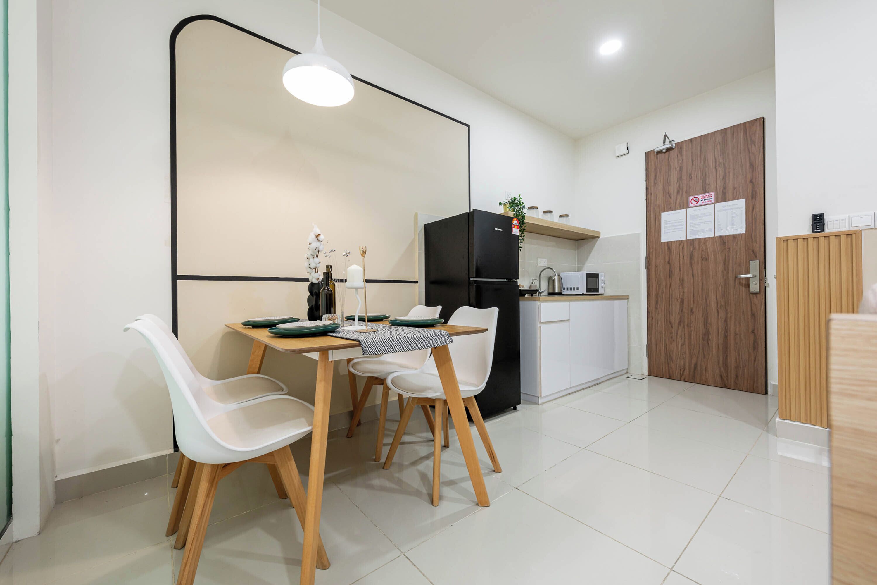 A modern kitchen with a black refrigerator, white chairs, and a dining table.
