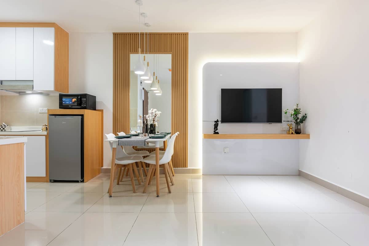 Una cocina moderna con comedor, microondas integrado, refrigerador y televisor de pantalla plana en la pared.