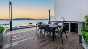A wooden deck with a table and chairs, overlooking a body of water and hills. - The Shore Premier Suites Kota Kinabalu (Kota Kinabalu)