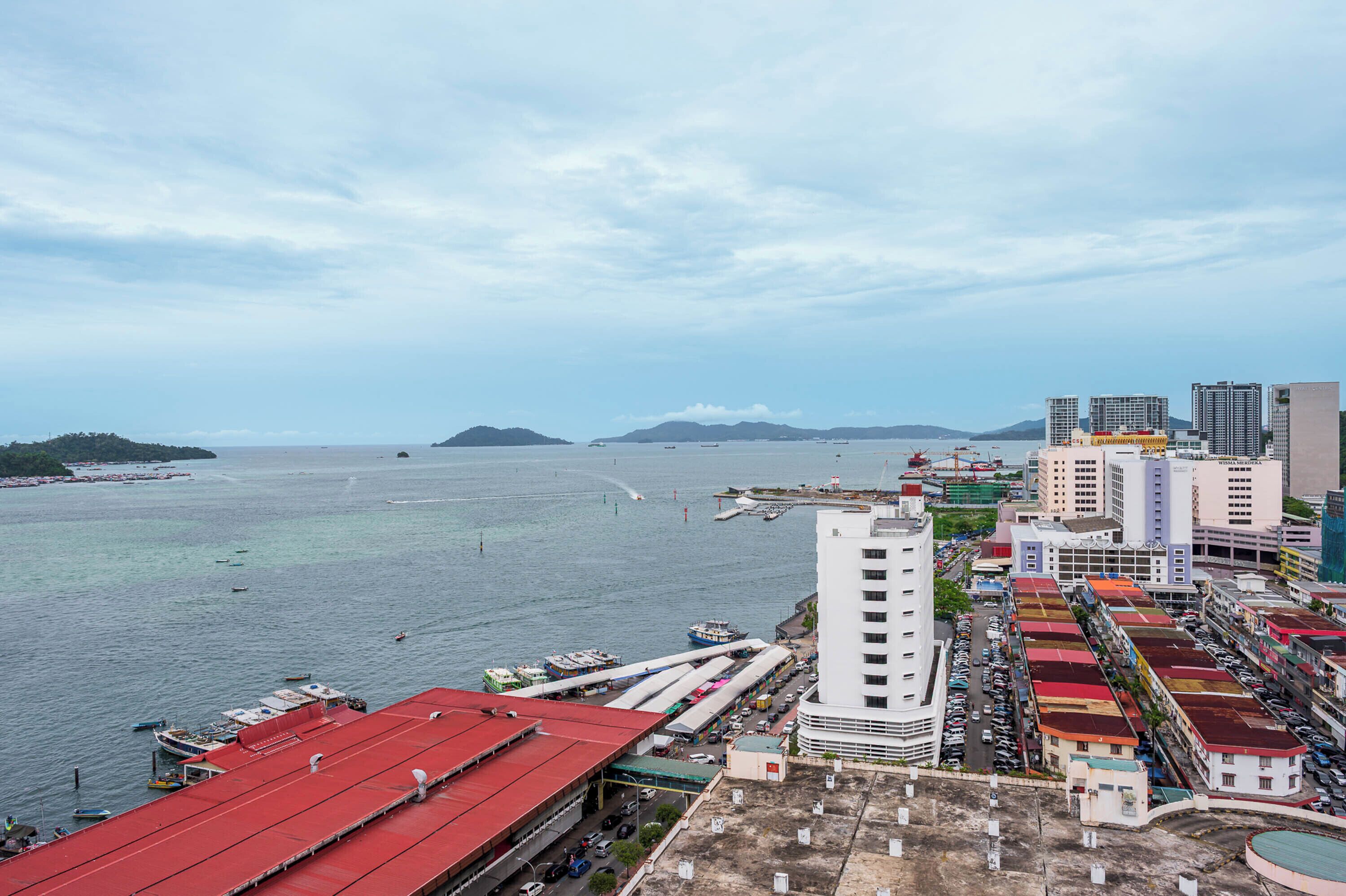 A coastal cityscape with a marina, high-rise buildings, and a prominent white tower.