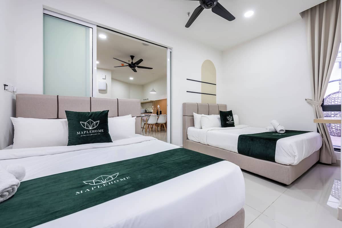 Habitación de hotel con dos camas, ventilador de techo, zona de comedor y vista al exterior.