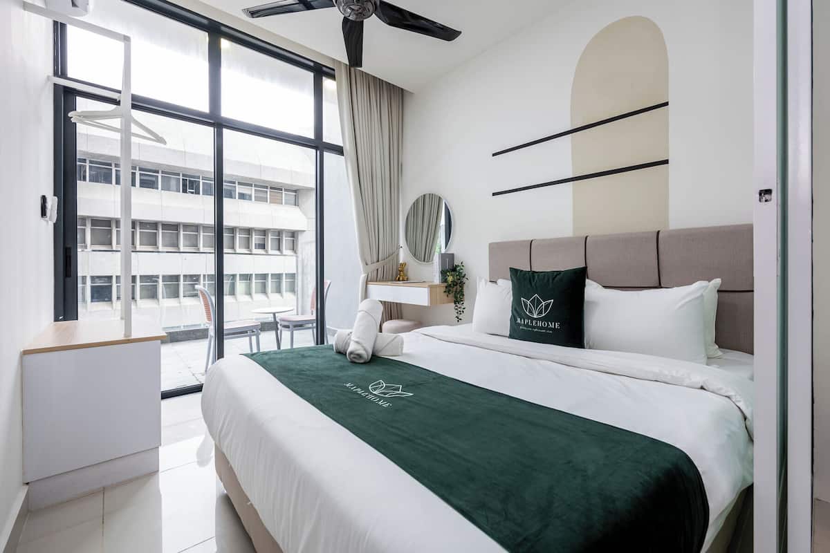 Habitación de hotel con cama, escritorio, silla, ventana y vista a un edificio.