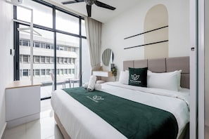 A hotel room with a bed, a desk, a chair, a window, and a view of a building outside.