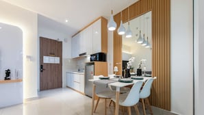A modern kitchen with white cabinets, a microwave, and a dining area with a white table and chairs. - The Shore Premier Suites Kota Kinabalu (Kota Kinabalu)