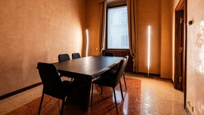 Ein Konferenzraum mit einem langen Tisch, Stühlen, einem Fenster mit Vorhängen und einer Tür.