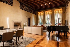 A spacious living room with a large wooden table, a piano, and a fireplace. - Luxurious Maffei Palace - Domus Verona (Verona)