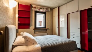 Ein Schlafzimmer mit Bett, Fenster, Ablage und Kleiderschrank.