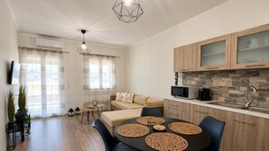Una cocina moderna con armarios de madera, un microondas y un lavamanos. Hay un comedor con una mesa redonda y sillas.