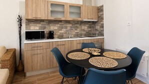 Una cocina compacta con armarios de madera, un microondas, una cafetera y una mesa de comedor con sillas azules.