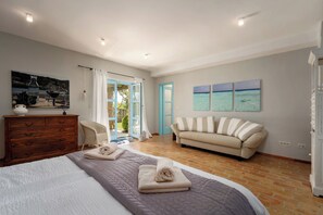 Ein Schlafzimmer mit Bett, Kommode, Sofa und einem Meeresbild.