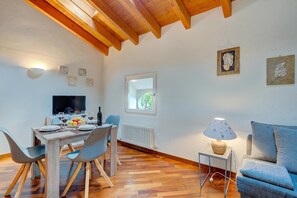 A dining area with a wooden table, chairs, and a television. - Palazzo Gritti Apartments (Morcote)