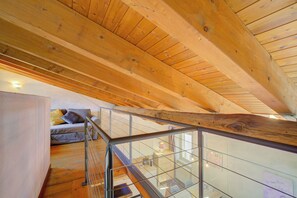 A wooden interior with a glass railing, a sofa with cushions, and a dining area. - Palazzo Gritti Apartments (Morcote)