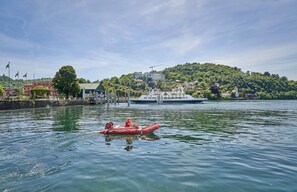 Une rivière paisible, avec un petit bateau pneumatique rouge et un grand navire de croisière amarré sur la rive.