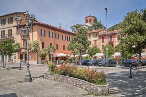 Una strada fiancheggiata da edifici, con un marciapiede in pietra e auto parcheggiate.