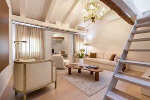 Ein modernes Wohnzimmer mit Sofa, Sessel, Couchtisch und einer Treppe.