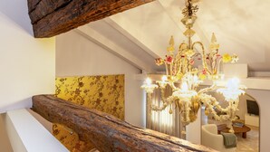 A room with a chandelier, a wooden beam, a floral wallpaper, and a sofa. - Peaceful Cannaregio Top-Floor Apartment Steps from Ca’ D’Oro (Venice)