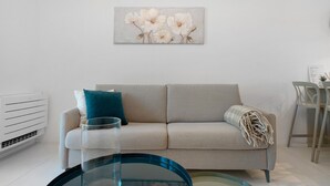 Een woonkamer met een bank, een glazen salontafel, een kunstwerk aan de muur en een radiator.